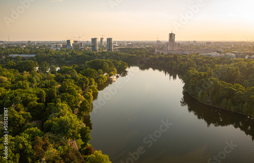 Bucharest from above, aerial view over Herastrau (King Michael I) Park, lake and the north part of the city with office building photographed during a summer sunset.