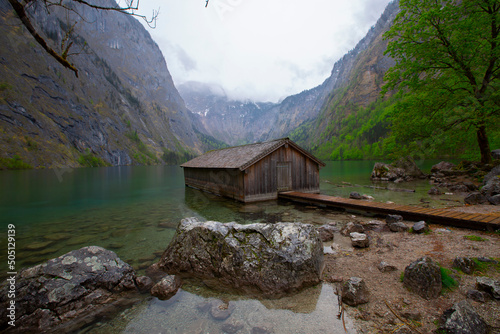 Idyllic view of traditional old wooden boat house at scenic Lake Obersee on a beautiful sunny day with blue sky and clouds in summer, Nationalpark Berchtesgadener Land, Bavaria, Germany photo