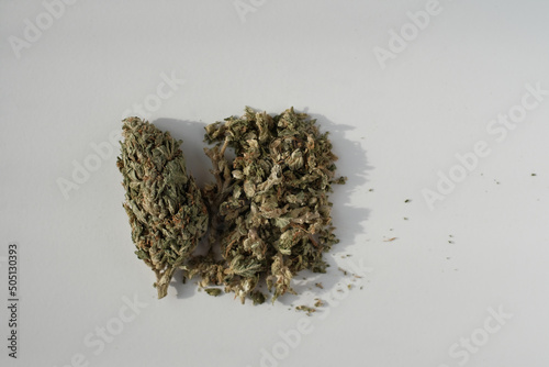Cannabis bud with crushed medical marijuana cone on white background