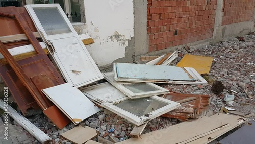 Old doors and windows removed from a construction site appear broken and abandoned, reflecting decay, demolition, and the contrast between past structures and urban renewal.