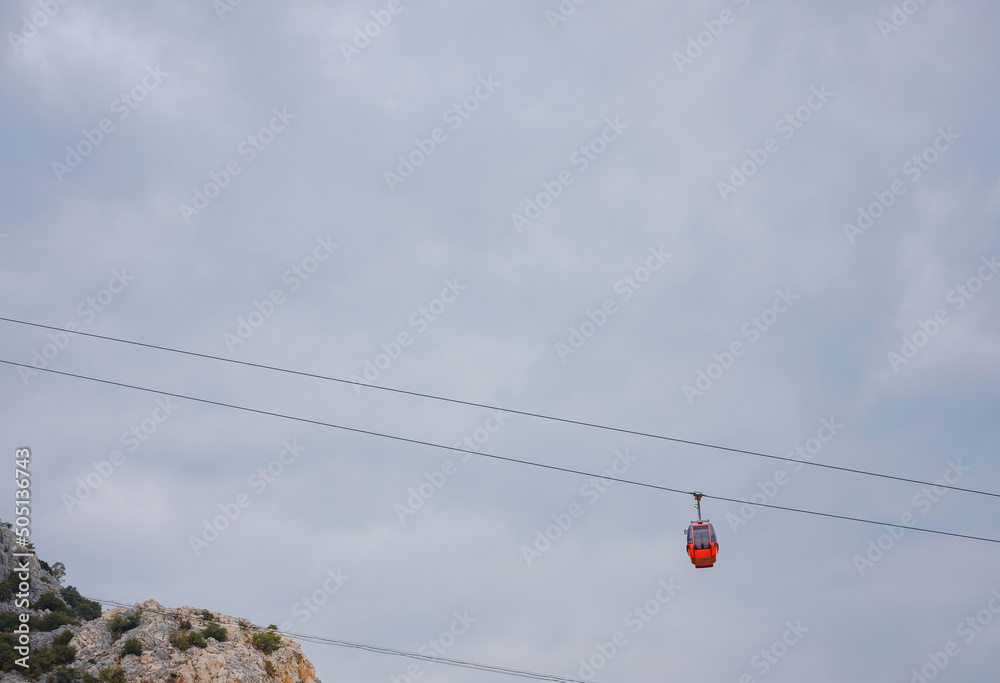 Red cabins of funicular in Antalya, Turkey against backdrop of rain clouds. Cable car trip to viewpoints in mountains. During trip by cable car Tourists enjoy beautiful views of city and nature Red cabins of funicular in Antalya, Turkey against backdrop of rain clouds. Cable car trip to viewpoints in mountains. During trip by cable car Tourists enjoy beautiful views of city and nature