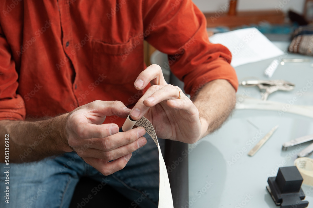 A Jewish scribe binds a scroll with Hebrew verses from the Bible before