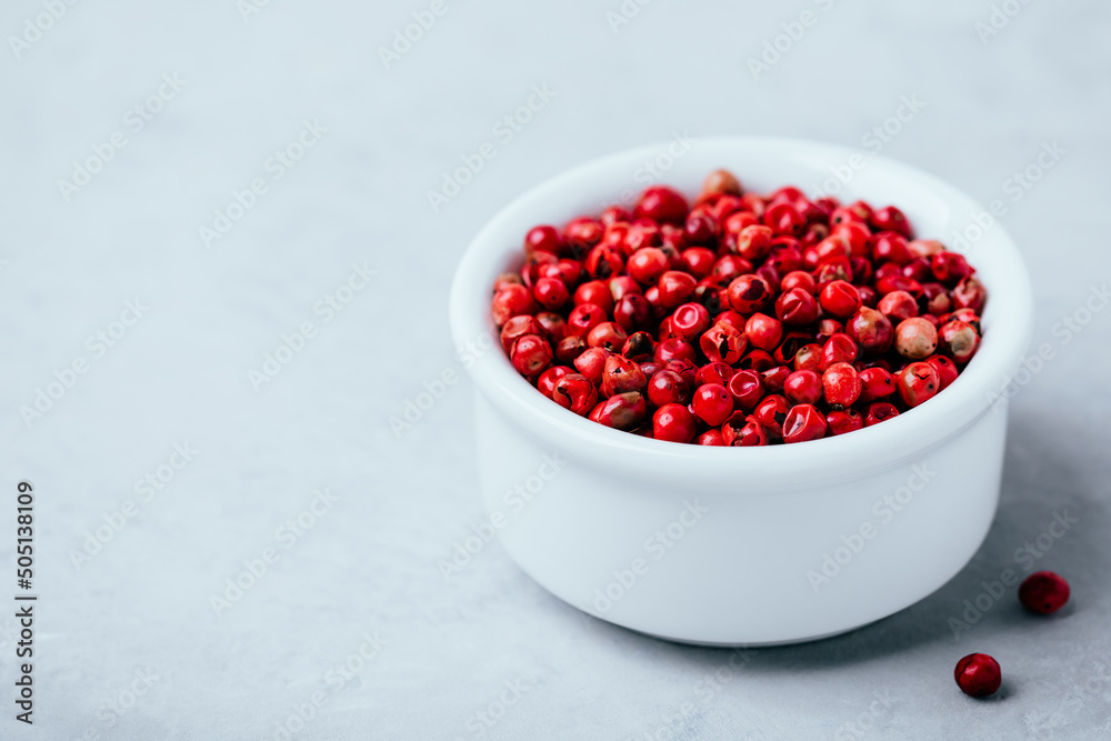 Pink peppercorn in white bowl on gray stone concrete background Pink peppercorn in white bowl on gray stone concrete background
