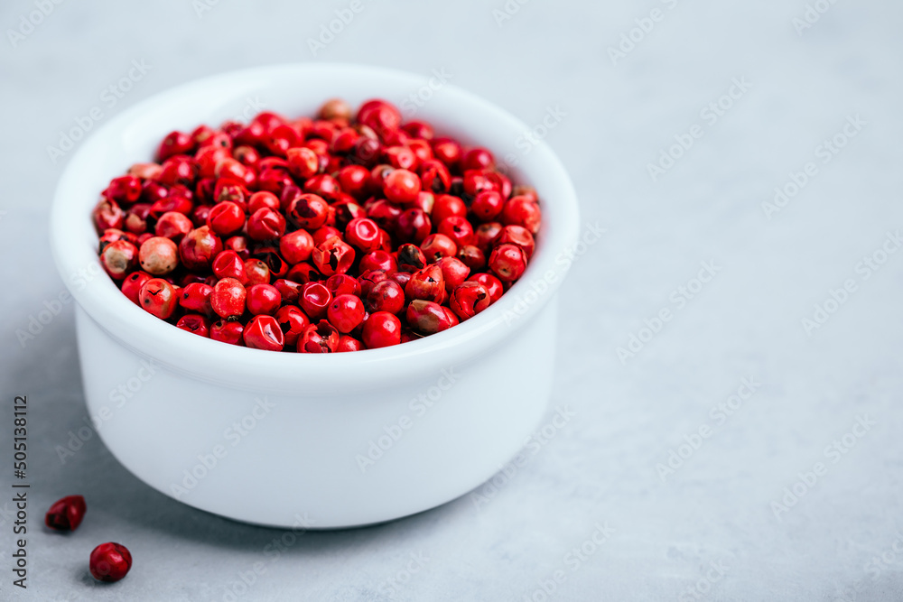 Pink peppercorn in white bowl on gray stone concrete background Pink peppercorn in white bowl on gray stone concrete background