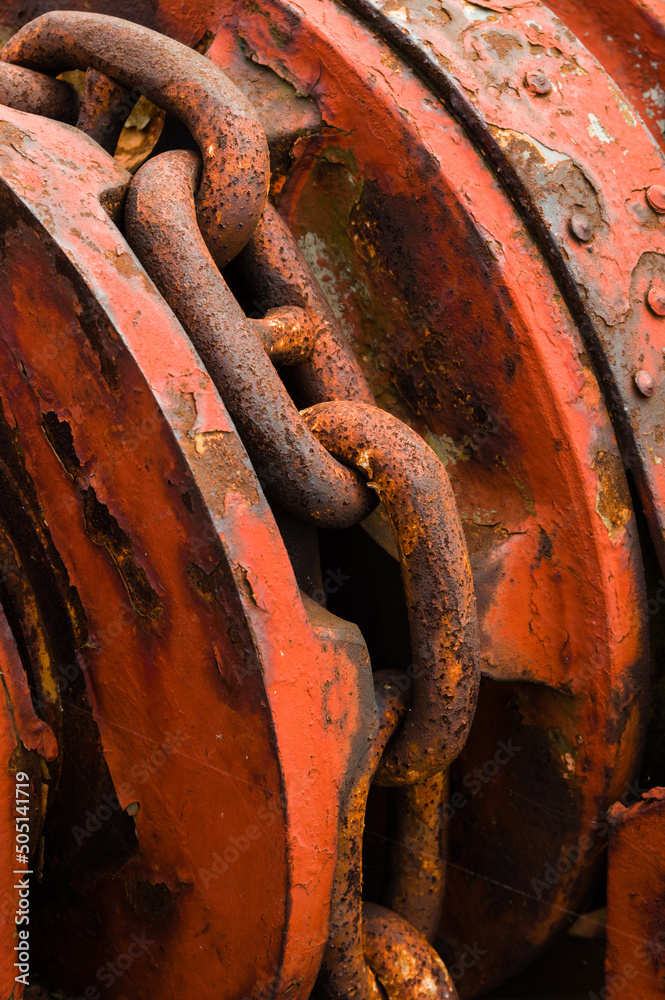 Strong rusty anchor chain on red metal winder Strong rusty anchor chain on red metal winder
