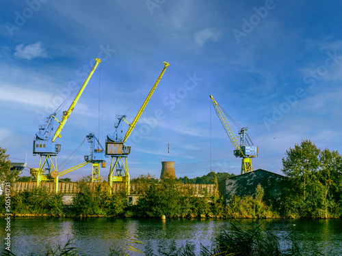 Caen, France, Normandy May 2022. Overhead gantries standing in the port of Caen next to the shipping channel. In the distance, a view of the old factory chimney at sunset. photo