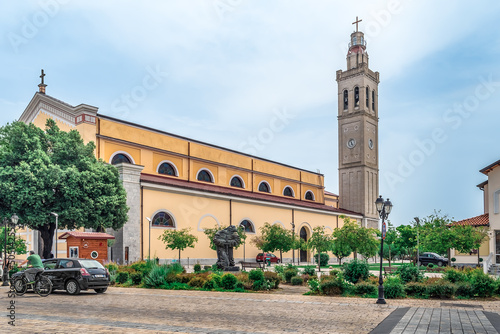 Shkoder, Albania - June 21, 2021: View from Rruga Marin Bicikemi street to St. Stephen Cathedral in Shkodra. Beautiful urban landscape with a sculpture of a monk on the backdrop of a Catholic church photo