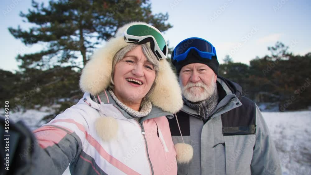 life after retirement, modern elderly man and old woman communicate via video call using a mobile phone with friends while traveling in winter in forest among snow and trees life after retirement, modern elderly man and old woman communicate via video call using a mobile phone with friends while traveling in winter in forest among snow and trees