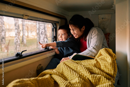 Foto A multicultural mother with her child lies on the bed in the van.