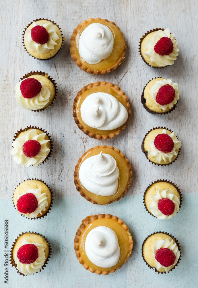 Mini cupcakes and lemon tarts on a wooden board from above. Mini cupcakes and lemon tarts on a wooden board from above.