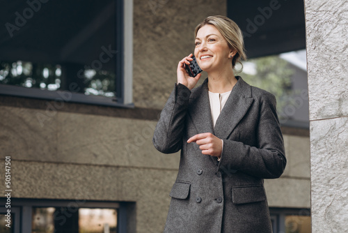 Portrait of a beautiful mature business woman smiling and talking on the phone on the modern urban background