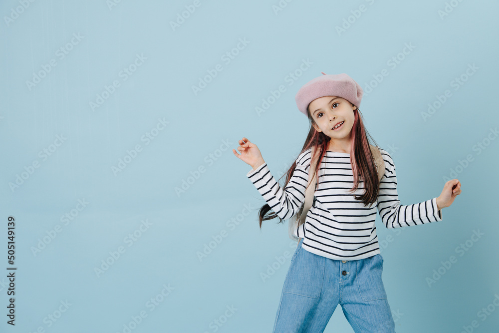 Goofy tween girl in french beret posing over blue background. Goofy tween girl in french beret posing over blue background.