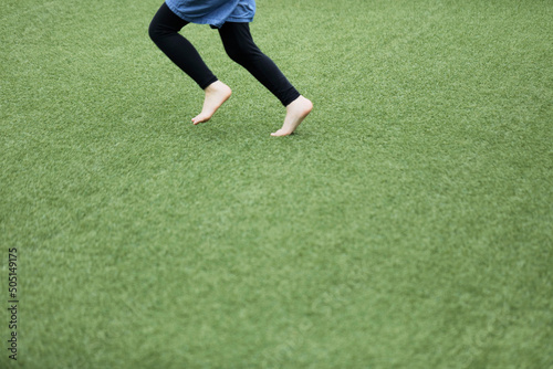 Legs of a girl running in green field. Space for copy.
