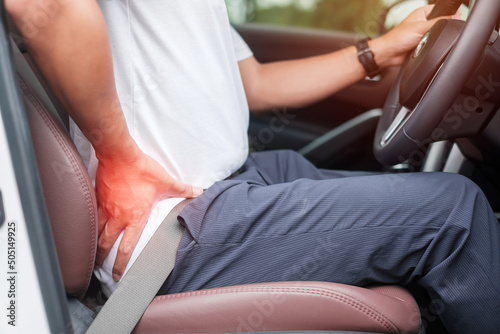 man with his back sprain while driving car long time, back body ache due to Piriformis Syndrome, Low Back Pain and Spinal Compression. Ergonomic and medical concept photo