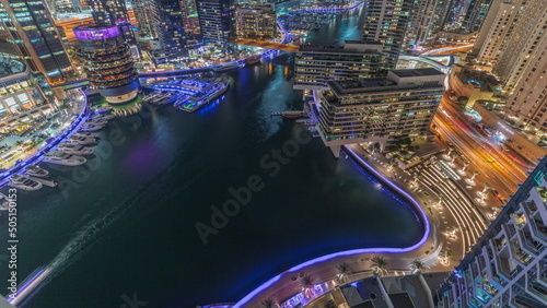 Aerial view to Dubai marina skyscrapers around canal with floating boats night timelapse