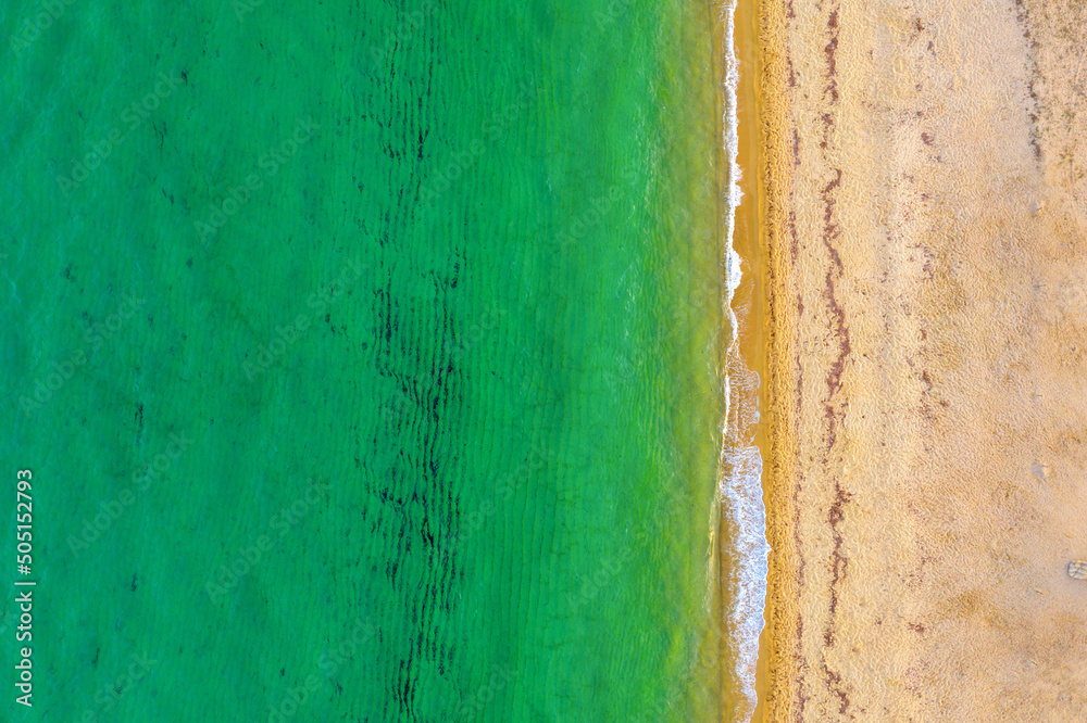 Top view of beautiful beach. Aerial drone shot of turquoise sea water at the beach on a sunny day. Top view Sandy coastline with white turquiose sea waves. Summer sunset seascape..