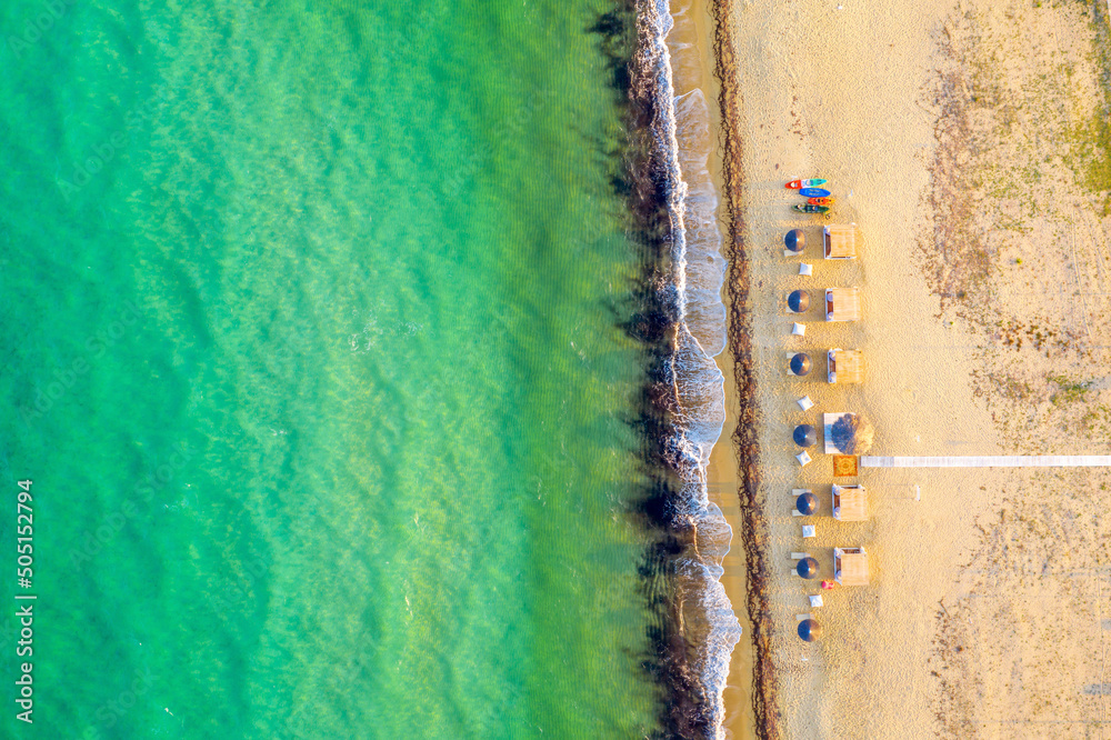 Aerial view of sea and sand beach on a sunny day. Top view Sandy coastline with white turquiose sea waves. Summer sunset seascape...
