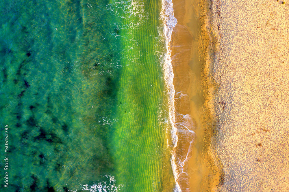 Top view of beautiful beach. Aerial drone shot of turquoise sea water at the beach on a sunny day. Top view Sandy coastline with white turquiose sea waves. Summer sunset seascape..