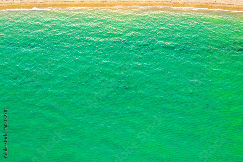 Obraz na płótnie Top view of beautiful beach. Aerial drone shot of turquoise sea water at the beach on a sunny day. Top view Sandy coastline with white turquiose sea waves. Summer sunset seascape.. w salonie