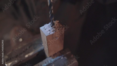 Blacksmith drilling a hole into the wood. Damascus steel knife.