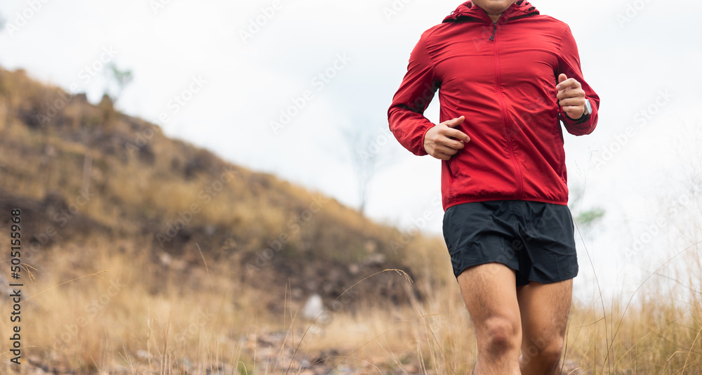 Trail runner man running on rocky mountain. Athlete jog exercising outdoor for healthy. Confident and powerful marathon man running workout and cardio. Sport and Lifestyle concept.