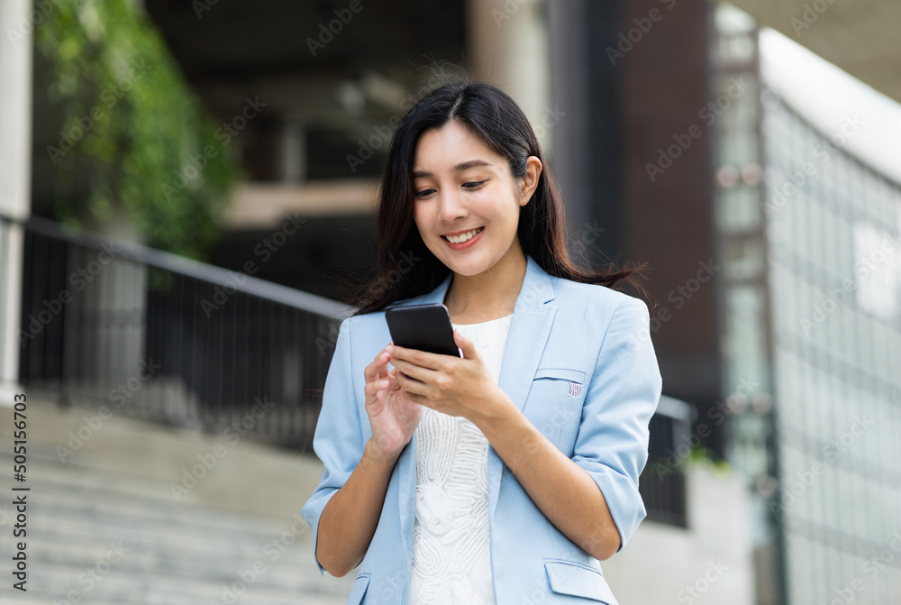 Beautiful business woman using mobile phone to play social media in the buildings at downtown. Smart female using cell phone chatting for business communication. Smartphone concept. Beautiful business woman using mobile phone to play social media in the buildings at downtown. Smart female using cell phone chatting for business communication. Smartphone concept.
