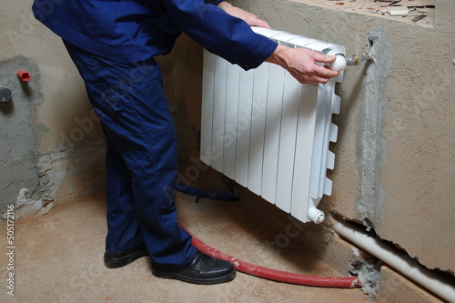 Plumber worker installing heating radiator