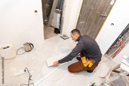 Repairman laying laminate flooring at home.