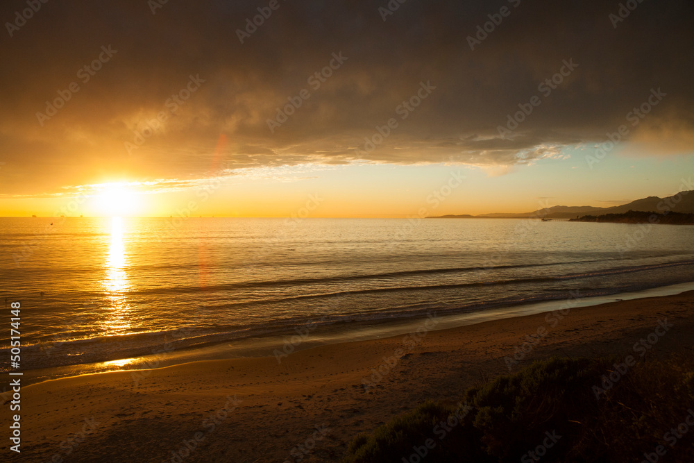 Winter sunset with golden light under heavy storm clouds. Looking out to the Pacific ocean near Ventura, California, USA