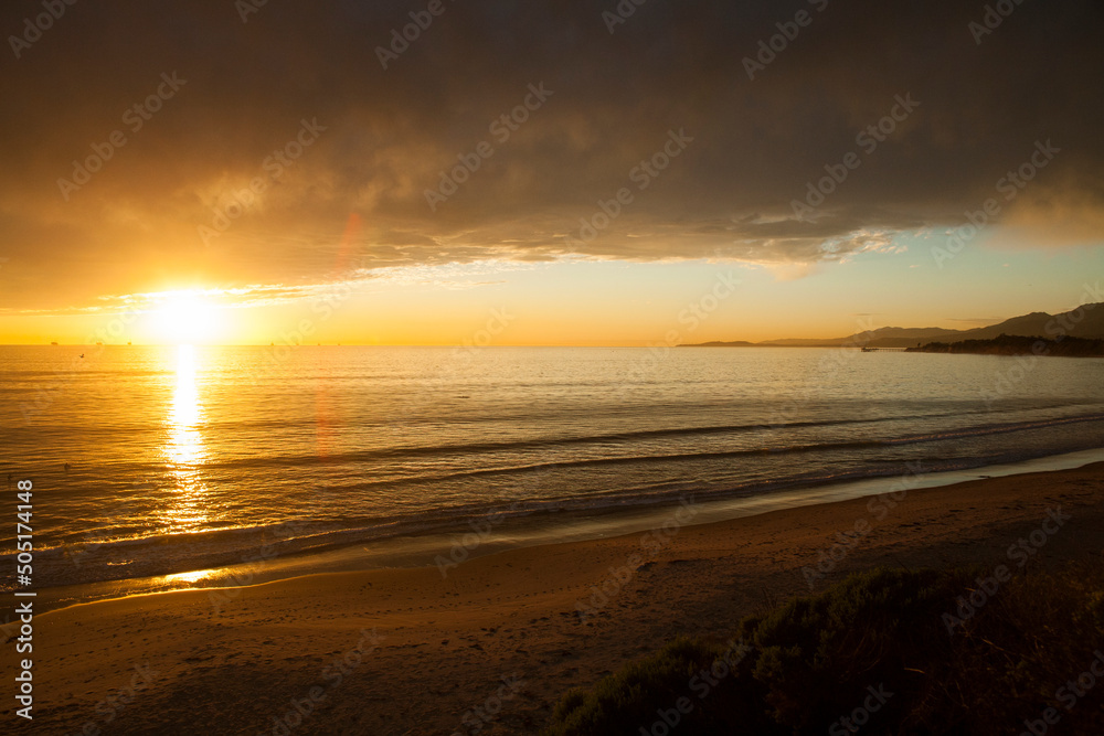 Obraz premium Winter sunset with golden light under heavy storm clouds. Looking out to the Pacific ocean near Ventura, California, USA