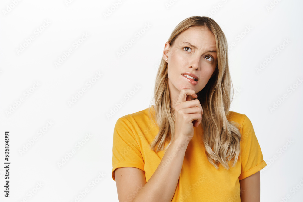 Beautiful candid girl with blond hair, smiling and thinking, making decision, choosing smth, standing thoughtful over white background Beautiful candid girl with blond hair, smiling and thinking, making decision, choosing smth, standing thoughtful over white background