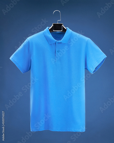 Volume polo shirt hanging on hanger, dark blue background colours, blue, sky blue, blue.