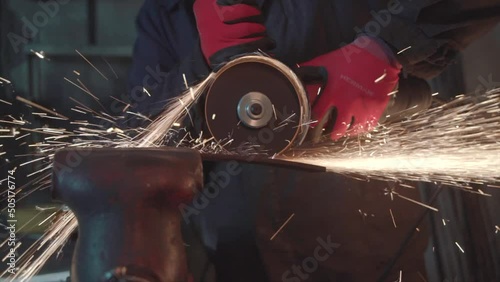 Blacksmith cutting metal plate in smithy workshop. Damascus steel knife.