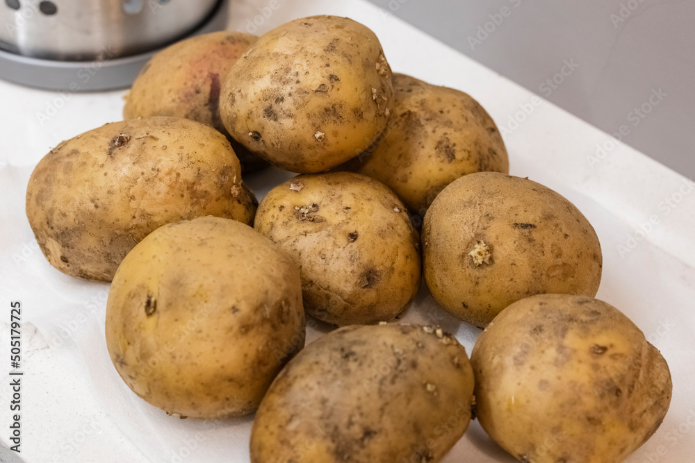 Heap of potatoes with skins on the kitchen table with focus blur. Close-up Heap of potatoes with skins on the kitchen table with focus blur. Close-up