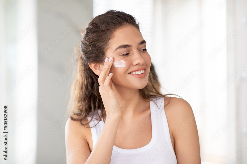 Young Lady Caring For Skin Applying Moisturizer Cream At Home Young Lady Caring For Skin Applying Moisturizer Cream At Home