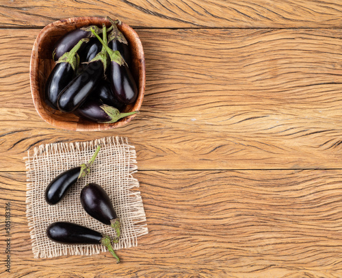 Tiny baby eggplants in a bowl over wooden table with copy space