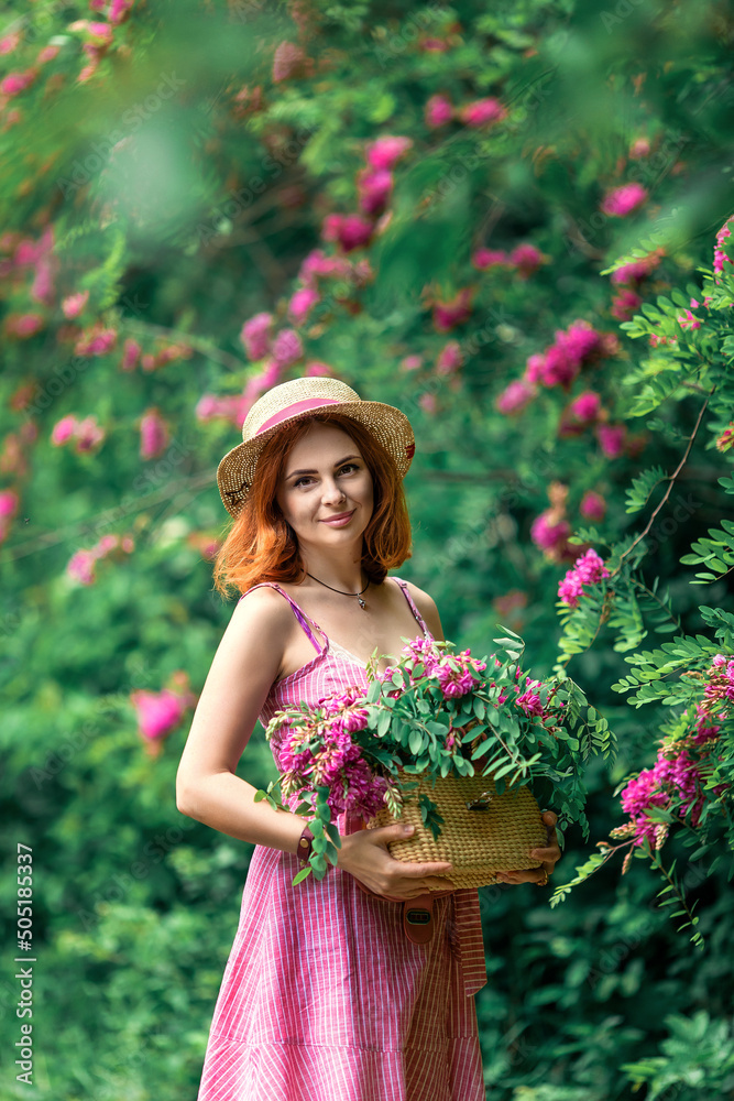 Natural beautiful red-haired girl holds on hands basket with garden flowers