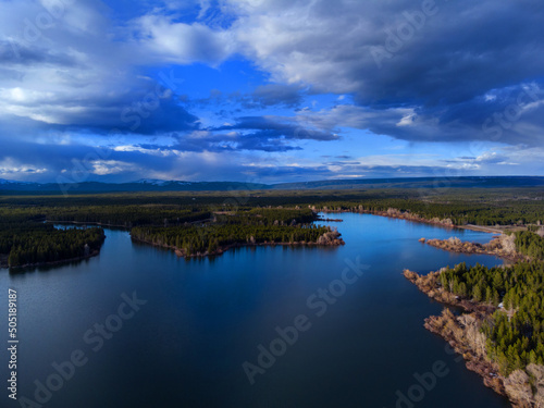 Fototapeta Naklejka Na Ścianę i Meble -  Aerial View from a Drone Flying above a Lake with Forest and Sky