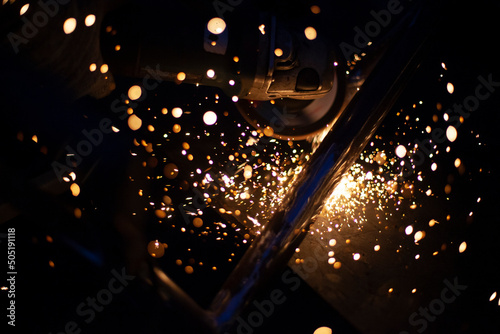Sparks from grinding metal. Steel processing in workshop. Lights in dark. Production of parts. Cutting became grinder.