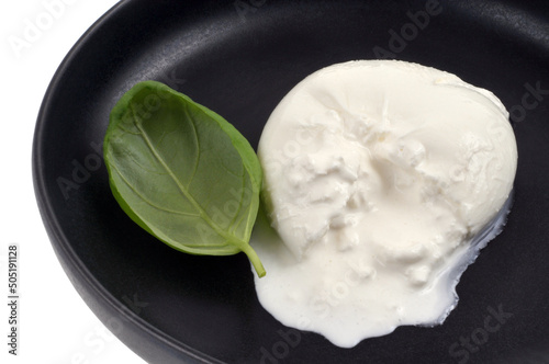 Burrata di bufala ouverte avec une feuille de basilic en gros plan dans une assiette noire photo