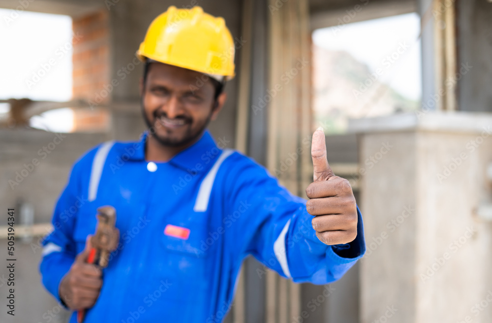 plumber with pipe and plumbing tool in hand showing thumb by looking at camera - concept of serviceman ready to work, Confidence and Profesional occupation. plumber with pipe and plumbing tool in hand showing thumb by looking at camera - concept of serviceman ready to work, Confidence and Profesional occupation.