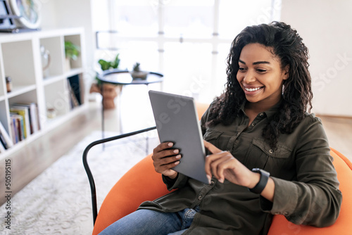 Portrait of smiling black woman using digital tablet at home