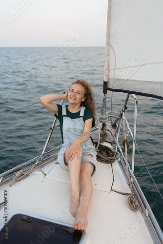 A young beautiful redhead woman is lying on the deck of a yacht at sea