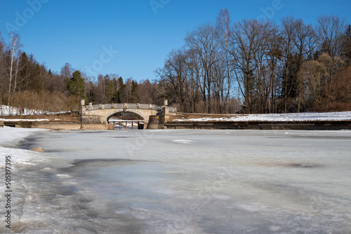 Vintage Viskontiev bridge over Slavyanka river. The spring landscape. Pavlovsk Palace Park. Saint-Petersburg, Russia photo