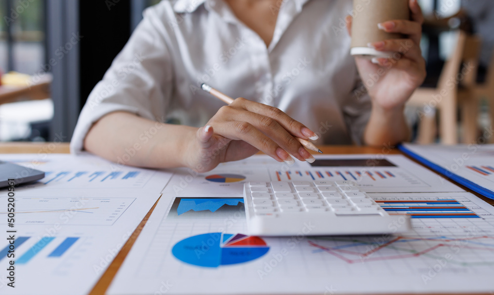 Fototapeta premium Businesswoman analyzing investment charts with calculator laptop. Accounting and technology in the office. Asian Business using laptop accountant Documents data partner deal in the workplace