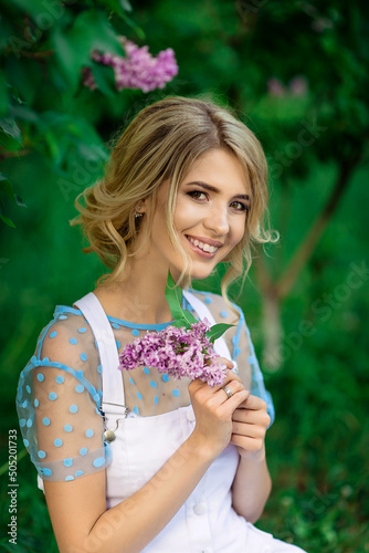 beautiful girl in nature holding a sprig of lilac