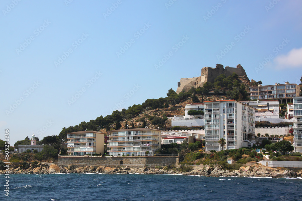 Old lighthouse, Trinity castle and holiday apartment houses at the coast of Roses city, Catalunya in Spain