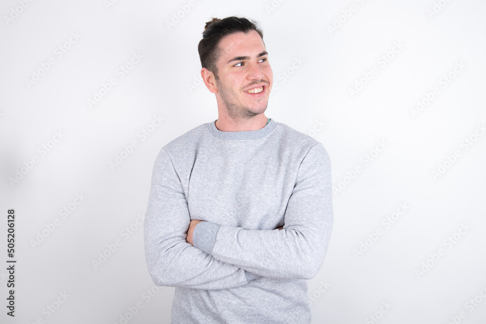 Dreamy rest relaxed Young handsome dark haired man wearing fitted T-shirt over white wall crossing arms, looks good copyspace Dreamy rest relaxed Young handsome dark haired man wearing fitted T-shirt over white wall crossing arms, looks good copyspace