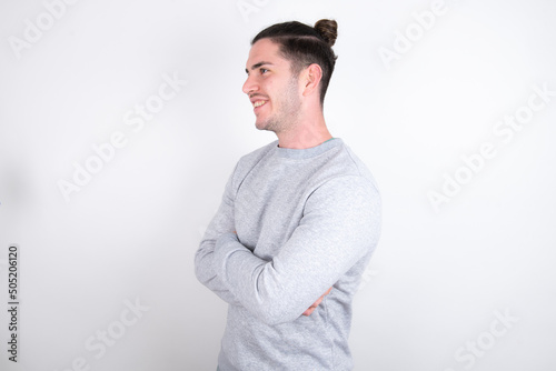 Young handsome dark haired man wearing fitted T-shirt over white wall cross hands look copy space