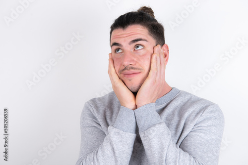 Inspired Young handsome dark haired man wearing fitted T-shirt over white wall looking at copyspace having thoughts about future events © Roquillo